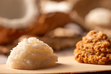 Open coconut and coconut sweets (cocadas) placed on a rustic wooden surface, selective focus.
