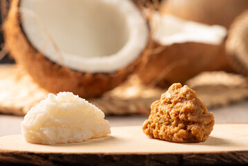 Open coconut and coconut sweets (cocadas) placed on a rustic wooden surface, selective focus.