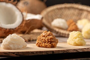 Open coconut and coconut sweets (cocadas) placed on a rustic wooden surface, selective focus.