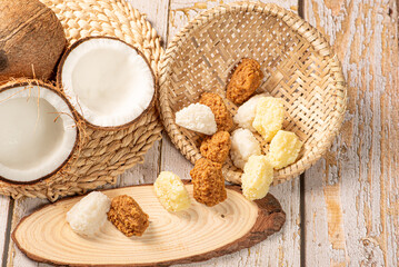 Open coconut and coconut sweets (cocadas) placed on a rustic wooden surface, selective focus.