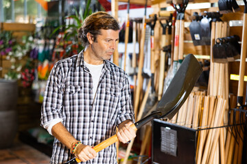 Fototapeta premium Caucasian farmer choosing shovel in garden shop