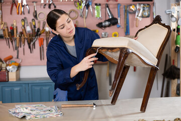 Portrait of skillful repair woman carpenter renovating chair furniture using tools in woodwork studio