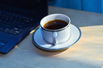 A cup of black coffee on the table with the morning sun