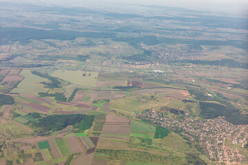 High altitude patchwork of agricultural fields and small villages. Landscape is a mix of cultivated land, scattered forests and small town. Aerial view of agricultural land and small settlements