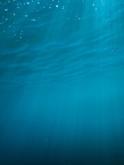 Ocean blue underwater with sunrays, Underwater Sea Deep Water Abstract Sunshine, sea wave , clean waters in summer time, Natural underwater seascape, sand on ocean floor and water surface with sunligh