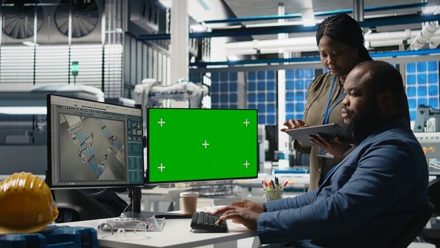 Professionals brainstorming solutions with mockup screen in solar facility, advancing industrial goals through collaboration and corporate responsibility. Team of engineers share insight. Camera A.