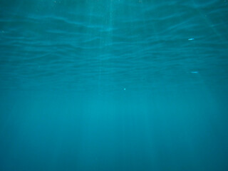 Ocean blue underwater with sunrays, Underwater Sea Deep Water Abstract Sunshine, sea wave , clean waters in summer time, Natural underwater seascape, sand on ocean floor and water surface with sunligh