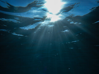 Ocean blue underwater with sunrays, Underwater Sea Deep Water Abstract Sunshine, sea wave , clean waters in summer time, Natural underwater seascape, sand on ocean floor and water surface with sunligh