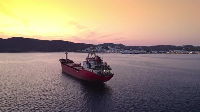 Orbit around cargo ship at sunset in front of harbor and mountains 4K