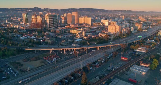 Aerial view of Oakland at sunrise. Cars travel on the highway, with the city skyline and residential areas in the background.  Oakland, California, USA. 11 May 2025.