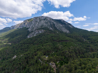 Aerial view of Sarıçalı Mountain in Nallıhan, Ankara National Park, showcasing lush green forests, rocky cliffs, and a beautiful sky with scattered clouds in a pristine natural environment.