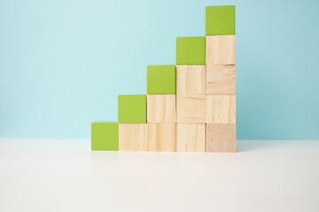 Ascending green and wooden blocks forming a staircase design, symbolizing growth, progress, and creativity. Versatile wooden cubes on clean background for business, health and education concepts. © BEN HDA