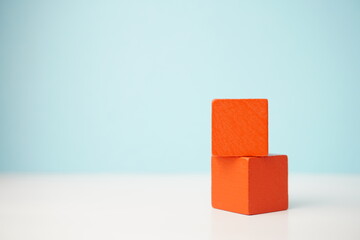 Two orange wooden cubes stacked against a blue backdrop, showcasing versatile wooden cubes on clean...
