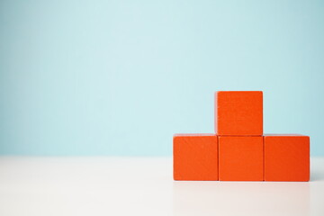 Stacked red wooden blocks on a clean surface with a blue background. Versatile wooden cubes on...