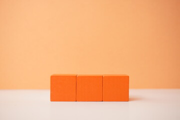Three orange cubes aligned on a minimalist backdrop, offering versatile wooden cubes on clean background for business, health and education concepts.
