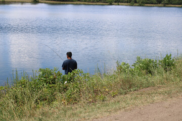 Man fishing in summer at Axehead Lake in Park Ridge, Illinois