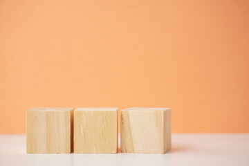 Three wooden blocks aligned against an orange background, symbolizing structure, creativity, and simplicity. Versatile wooden cubes on clean background for business, health and education concepts.