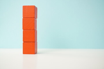 Stacked red wooden blocks forming a tower, set against a clean blue background, symbolizing balance and growth. Versatile wooden cubes on clean background for business, health and education concepts.
