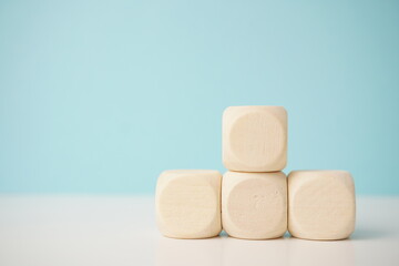 Minimalistic arrangement of smooth wooden blocks on pastel blue background, conveying simplicity and creativity. Versatile wooden cubes on clean background for business, health and education concepts.