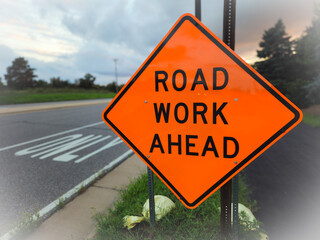A road work ahead sign against a trail and street backdrop, for warning or informational purpose. message or communication design element with copy space. abstract improvement concept