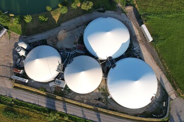 Aerial view of a rural agricultural complex with barns, biogas production domes, and storage tanks, highlighting bio renewable energy generation, sustainable farming, and clean energy infrastructure. © Semi