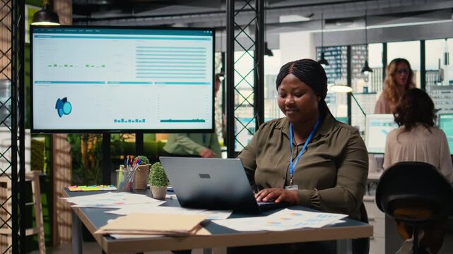 Business consultant analyzing financial data and writes reports in a sleek office, developing the company activity by evaluating the financial situation with graphs and insights on laptop. Camera A.