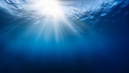 Fototapeta premium abstract image of tropical underwater dark blue deep ocean wide nature background with rays of sunlight and blue sky in background