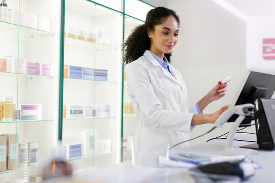 Beautiful lady pharmacist using checkout counter computer, doing inventory checkup, online prescription of medicine packages
