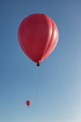 Fototapeta premium Crimson balloon ascends against clear blue sky, high, event