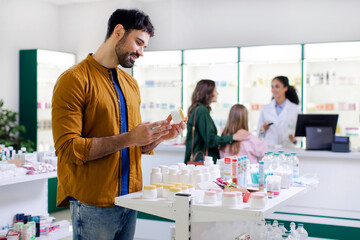 Obraz premium Man looking and choosing pills in pharmacy, shopping for medical treatment supplies. Medicine, pharmaceutical and health care