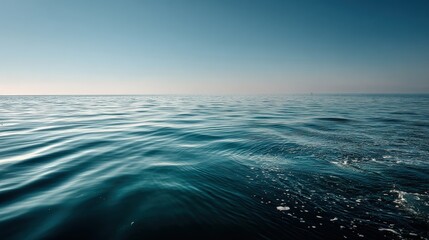 Obraz premium Tranquil open ocean view with gentle waves under clear blue sky showing calm sea horizon and water surface in serene natural setting du daytime