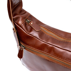 Naklejka premium Brown leather sling bag detail isolated on white background, perfect for leather product catalog design