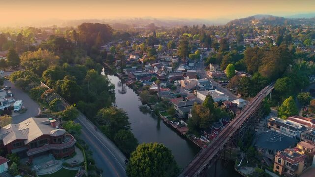 Aerial view of a river running through a residential neighborhood with a train trestle in Capitolia, California, USA.. Houses line the riverbanks.