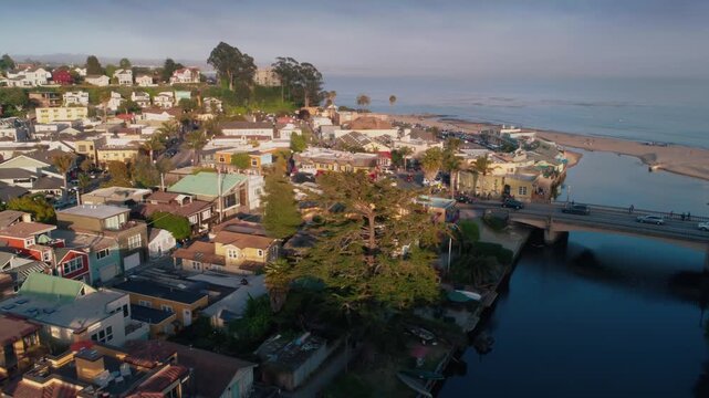 Aerial view of Capitola, California, USA, showing the town, beach, and Soquel Creek meeting the Pacific Ocean. A train bridge spans the creek in the foreground.
