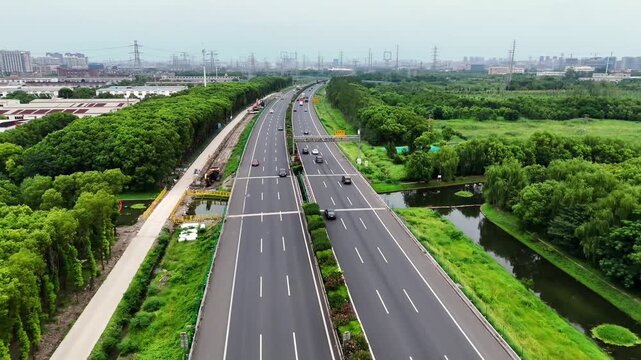 Dynamic 4K aerial footage of a busy multilane expressway with flowing traffic, overpasses, and surrounding green landscapes under a clear sky.