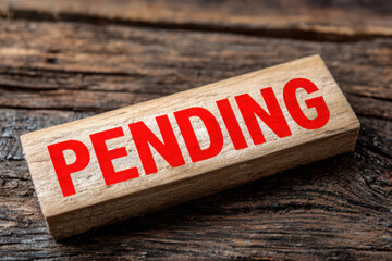 Wooden block with pending in red text on a rustic wooden surface close up studio shot for business use