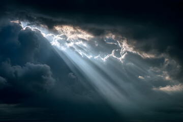 Light breaking through clouds creating ethereal rays in the dark, expansive atmosphere