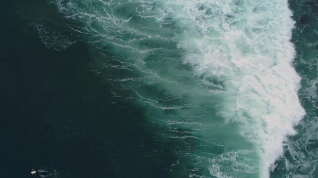 A surfer rides a large wave in Steamer Lane, Santa Cruz, California, USA. The aerial view shows the power of the ocean and the skill of the surfer as they navigate the turbulent water.