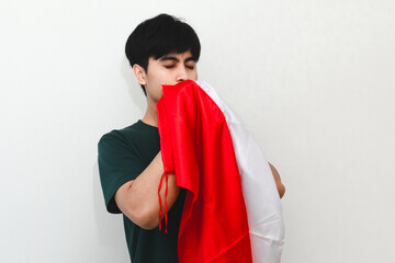 Indonesian man proudly kissing the national flag he holds, showing patriotic pride and love for the...