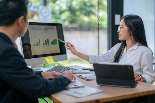 Businesswoman pointing at computer screen showing charts to businessman in office meeting - Powered by Adobe