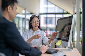 Businesswoman showing information on computer screen to businessman in office