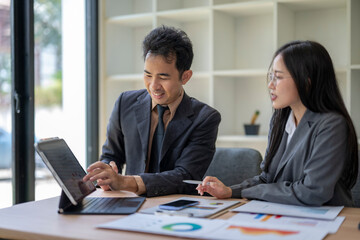 Business people analyzing statistics discussing financial results on tablet in office meeting
