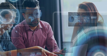 Four colleagues reviewing data on laptop in boardroom with green markers and digital overlays