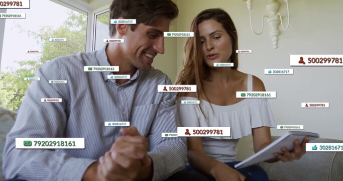 Man in striped shirt, woman in off-shoulder top examining tablet in living room, with data overlays - Powered by Adobe