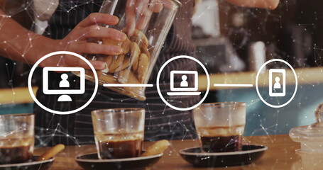 Pouring cookies barista wearing striped apron tilting glass jar at coffee counter, with tech icons