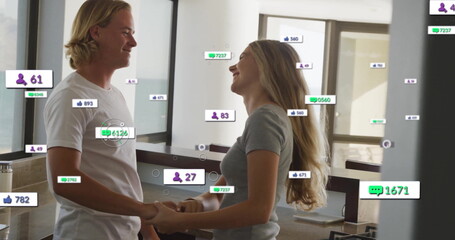 Holding hands couple smiling at each other at modern kitchen island, with floating digital icons