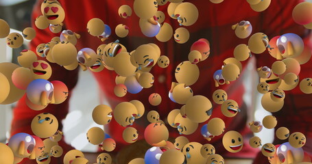 Standing man wearing red shirt in living room, with floating 3D emoji spheres and brown table