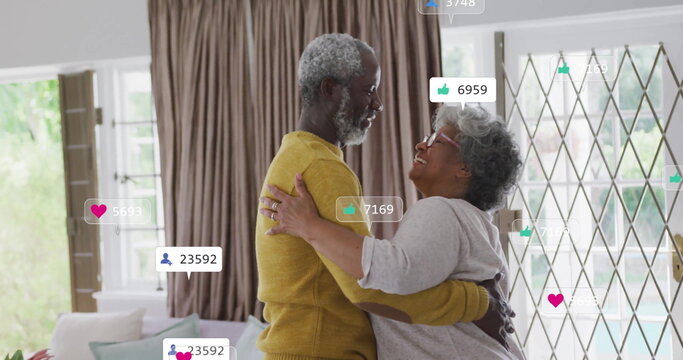 Dancing Senior couple embracing in living room, with sofa, curtains, sliding door, social overlays