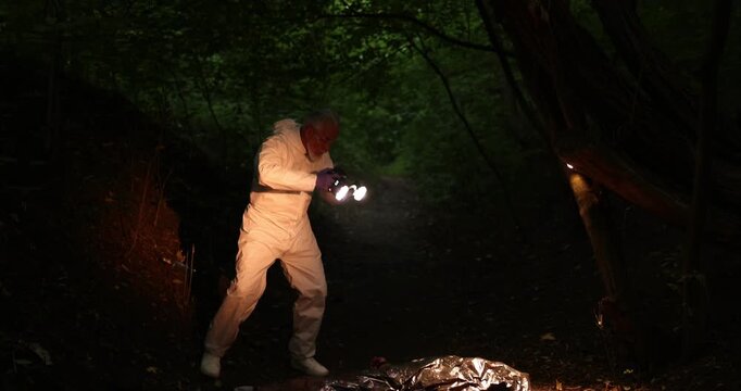 Forensic expert with camera working at crime scene with dead man's body outdoors, camera moving up
