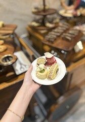 Hand Holding Plate of Afternoon Tea Treats